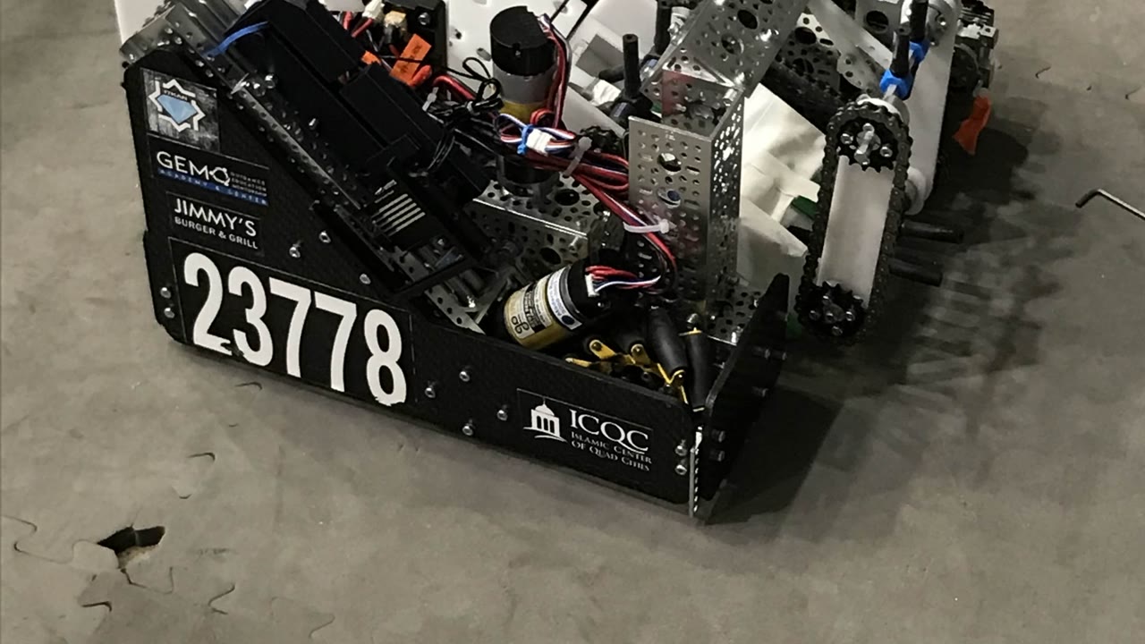 Close-up of the 23778 robot, its number in white on a black side panel carrying the GEMS, Jimmy's Burger and Grill and ICQC sponsor logos, with the chain drive and wiring visible above.